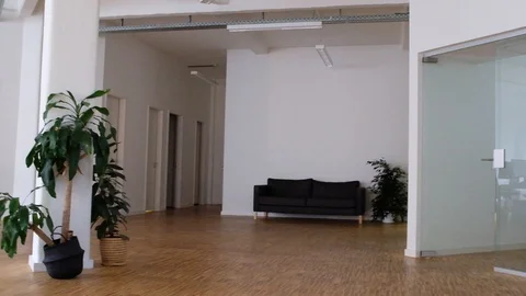 Handheld shot of young man pushing young woman on chair through office space 스톡 동영상 120423702