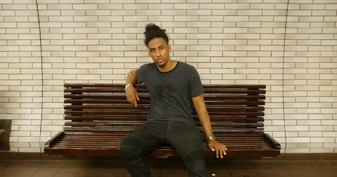 Handheld shot of young man sitting on bench Stock Footage 120149599
