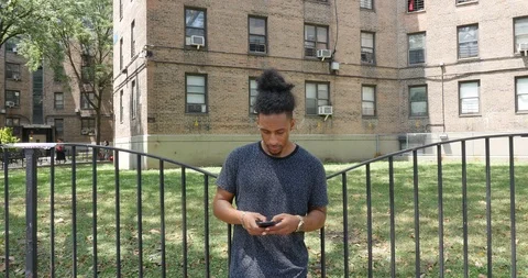 Handheld shot of young man standing against the gate on sidewalk Stock Footage 120071895