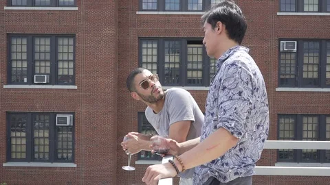 Handheld shot of young man talking with friend while standing in balcony Vídeo Stock 114878670