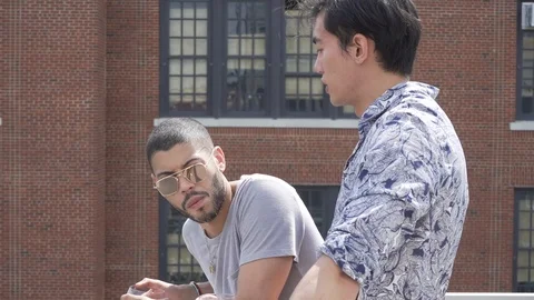 Handheld shot of young man talking with friend while standing in slow motion Stock Footage 114878671