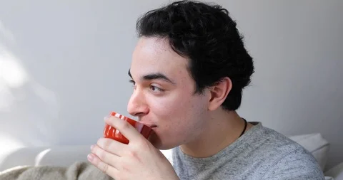 Handheld shot of young man talking and drinking coffee while sitting on sofa Stock Footage 120426583