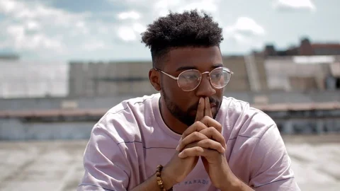 Handheld shot of a young man thinking while sitting in the building terrace 스톡 동영상 114880598