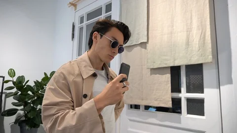 Handheld shot of young man trying sunglasses takes selfie at store 스톡 동영상 114849930