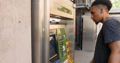 Handheld shot of young man using ATM on city street Stock Footage 120147524