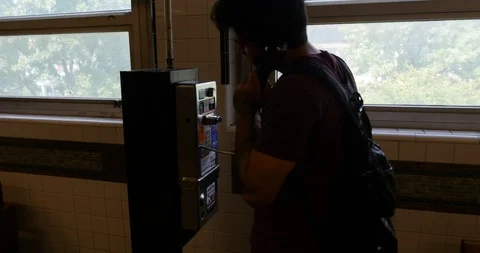 Handheld shot of young man using public phone and talking Stock Footage 120150387