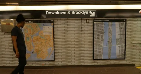 Handheld shot of young man walking past subway and city maps on wall Stock Footage 120150415