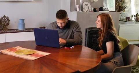 Handheld shot of young man working on laptop while girlfriend looking over Stock Footage 119935871
