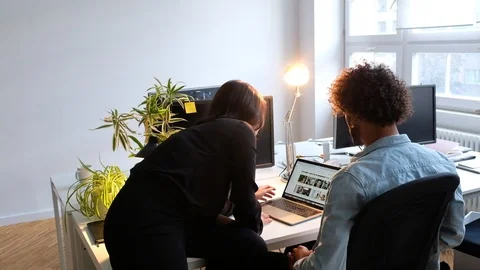 Handheld shot of young people talking while working on laptop in office 스톡 동영상 120433342