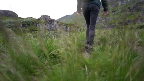 Handheld shot of a young woman walking on the grassy terrain Vídeo Stock 114881753