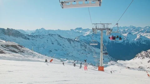 Handheld slo-mo ski slope with ski lift and people skiing and snowboarding Stock Footage 71124729
