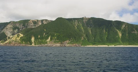 Handheld slow motion shot of blue sea with mountains covered in greenery, Japan Stock Footage 124716292