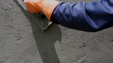Handheld slow-motion shot of close-up construction hand workers plastering ce Stock Footage 205542000