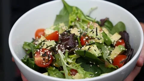 Handheld slow motion shot of green asian salad bowl held by two hands Stock Footage 155776032