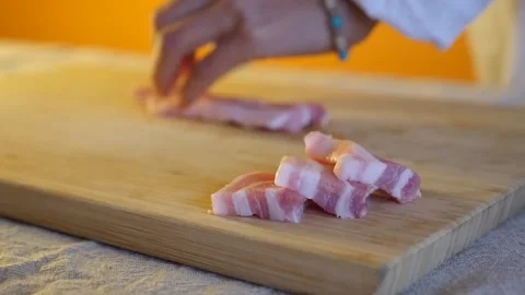 Handheld slow motion shot of pork belly getting cut on a bamboo cutting board Stock Footage 155776024