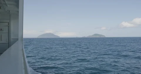 Handheld slow motion shot from ship of blue sea with two islands and sky, Japan Stock Footage 124720409