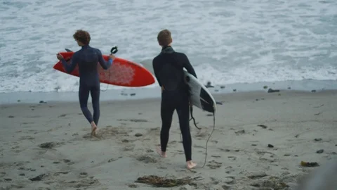 Handheld slow motion shot of two men warming up and preparing for surfing Stock Footage 120292881