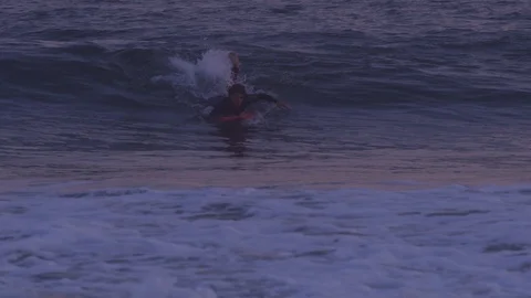 Handheld slow motion shot of a young adult paddling on surfboard sea waves Stock Footage 120286087
