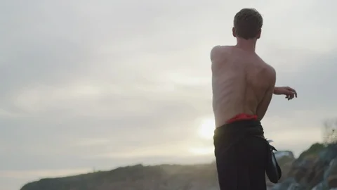 Handheld slow motion of surfer warming up and getting ready for surfing in sea Stock Footage 120292170