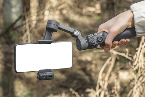 Handheld smartphone gimbal stabilizer in forest light. Mobile filming accesso Stock Photos