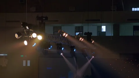 Handheld softfocus shot of ceiling spotlight shining in dark arena Video stock 113132687