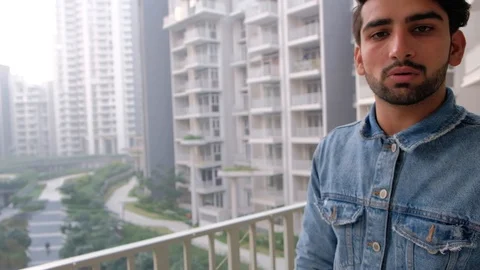 Handheld stabilized shot of young confident man showing high-rise multi storied  Stock Footage 101286620