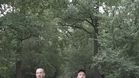 Handheld tilt down shot of three friends running on jogging track Stock Footage 114878283