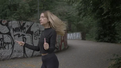 Handheld tilt down shot of young woman skipping rope Vídeo Stock 114843376