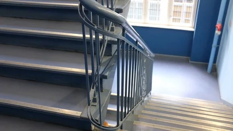 Handheld tilt up shot of two young women talking while going up stairs in office Stock Footage 120430327