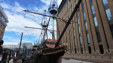 Handheld tracking shot past Golden Hinde replica between modern offices Stock Footage 346677183