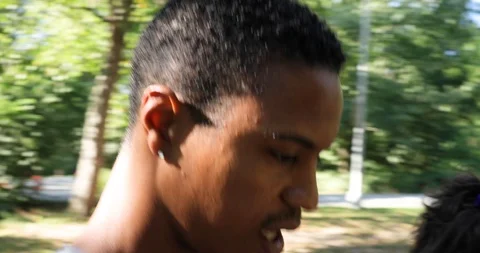 Handheld tracking shot of young couple walking together in park Stock Footage 120428799