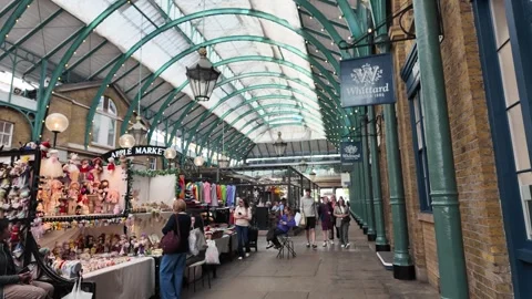 Handheld tracking through Covent Garden Apple Market arcade with shoppers Stock Footage 346678379