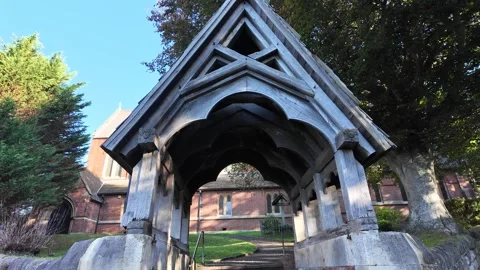 Handheld tracking under wooden lychgate at London church entrance Stock Footage 346676921