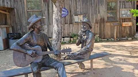Handheld video of 2 statues of mean on a bench in Luckenbach, Texas Vídeos de archivo 318638288