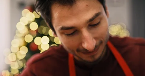 Handheld video shows of man decorating cookies in the kitchen Stock-Footage 121310140
