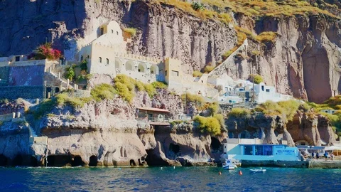 Handheld view of the coastal cliffs of Santorini as seen from a boat on the w 스톡 동영상 116089619