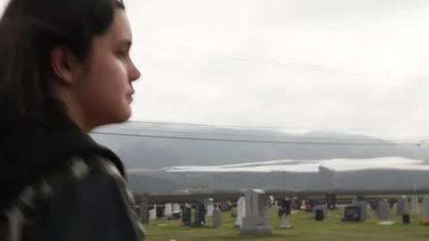 Handheld/doc style shot of kid walking around graveyard Stock Footage 155385037