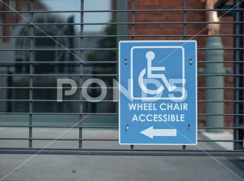 Handicap sign, wheel chair accessible logo pointing to left outdoor Stock Photos