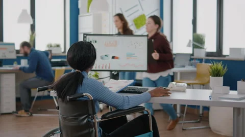 Handicapped african worker comparing graphics from clipboard and computer Stock Footage 154358983