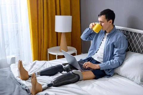 Handicapped guy using laptop for work or studies. New normal, social distancing Stock Photos