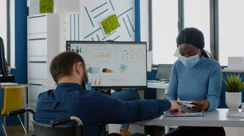 Handicapped office manager explaining to black colleague financial startegy Stock Photos