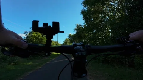 Handlebar perspective on quiet park cycling route. Tree lined asphalt path with Stock Footage 341568841