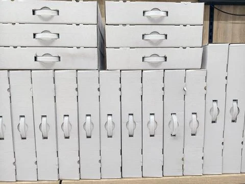 Handled white carton boxes displayed in structured rows on electronics stor.. Stock Photos