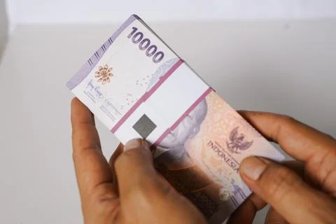 Handling a stack of ten thousand Indonesian Rupiah notes currency Photos