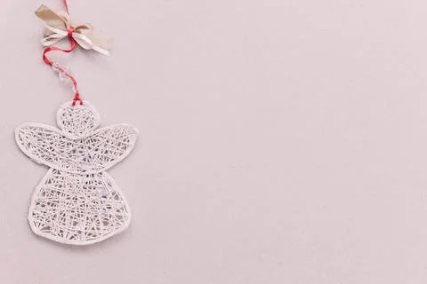 Handmade angel made of threads with a red ribbon on the left on a light blank Stock Photos