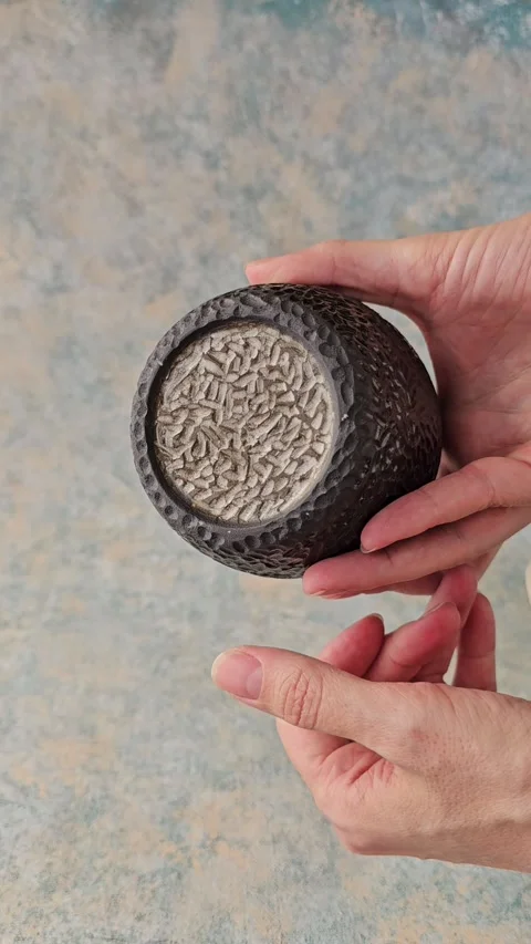 Handmade black ceramic cup with carved texture rotating in hands Video stock 324531486