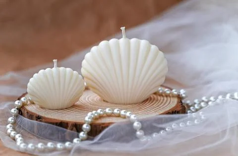 Handmade candles in the shape of a shell. Soy beige candles on wood, tulle an Stock Photos