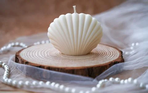 Handmade candles in the shape of a shell. Soy beige candles on wood, tulle an Foto stock