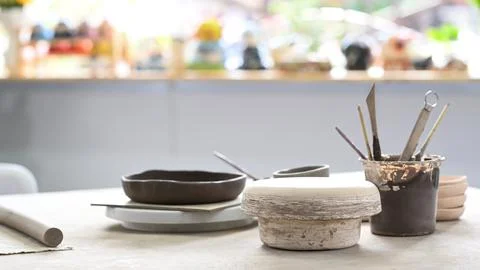 Handmade ceramic dish ware and pottery shaping tools on stone table in creative Stock Photos
