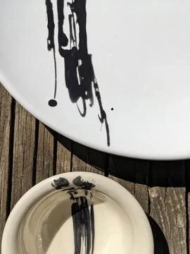 Handmade Ceramic Plates with Abstract Black Brushstrokes on Rustic Wood Stock Photos